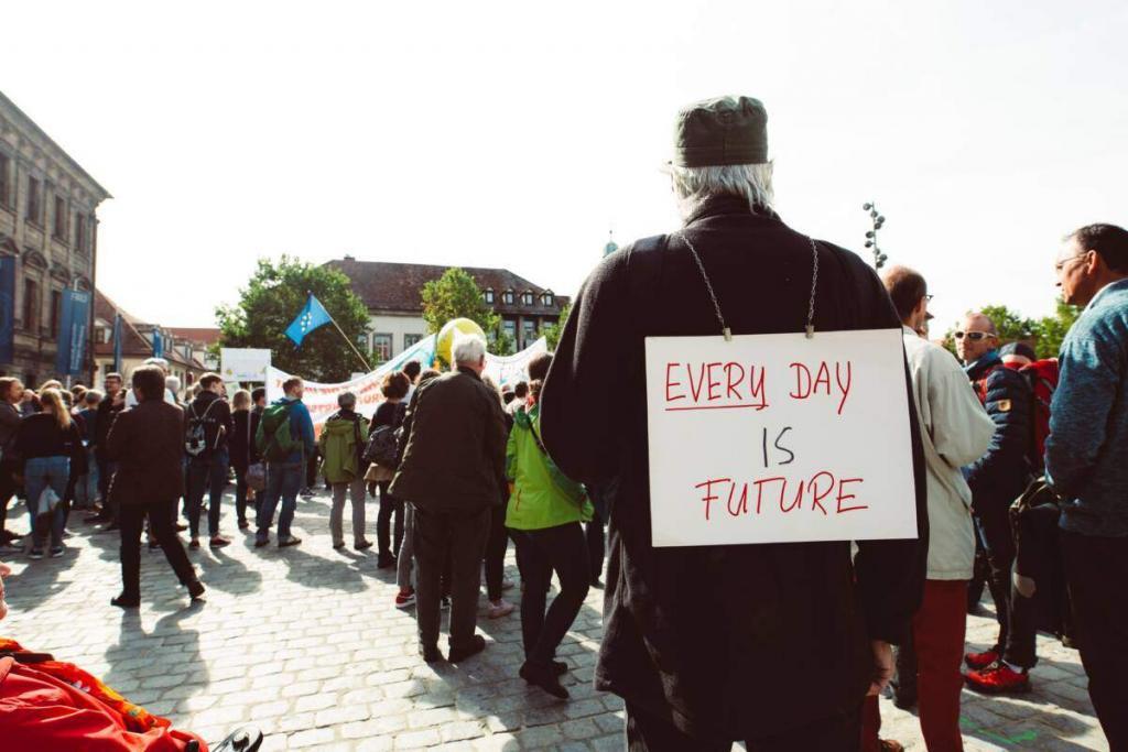 Man at demonstration wearing a sign that says "Every day is future".